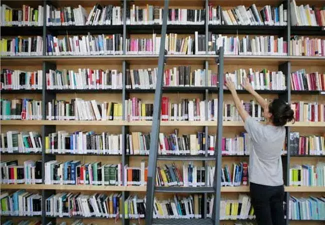 Mujer tomando un libro de una estantería 